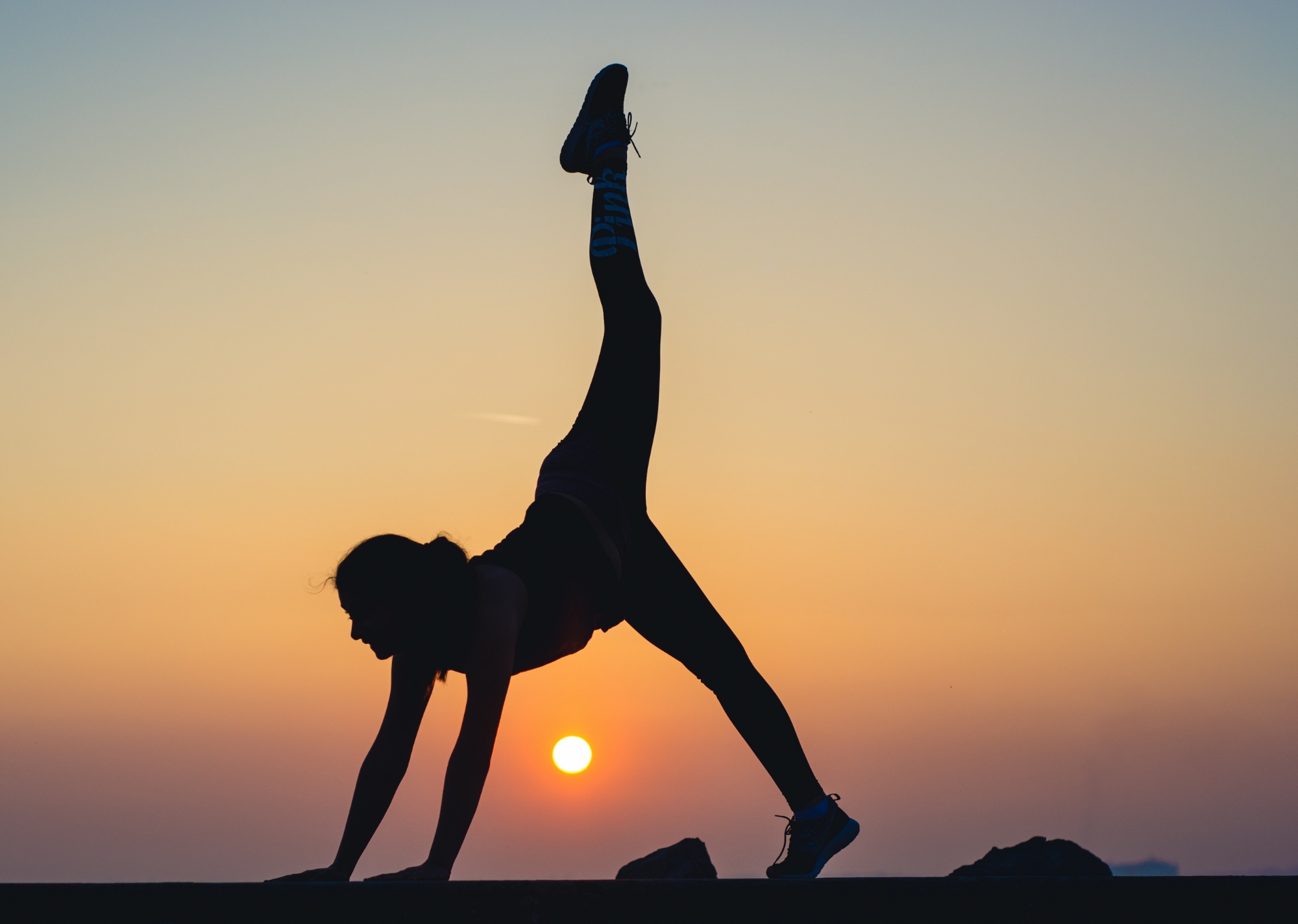 A UWC student performs a yoga movement as the sun sets behind her.